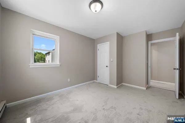 a view of an empty room with closet and a window