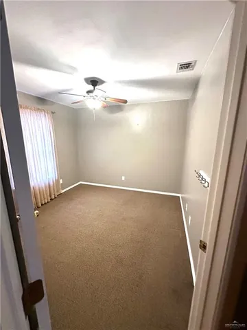 an empty room with a ceiling fan and a window