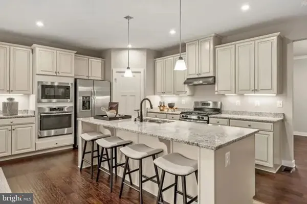 a kitchen with kitchen island granite countertop a table chairs sink and cabinets