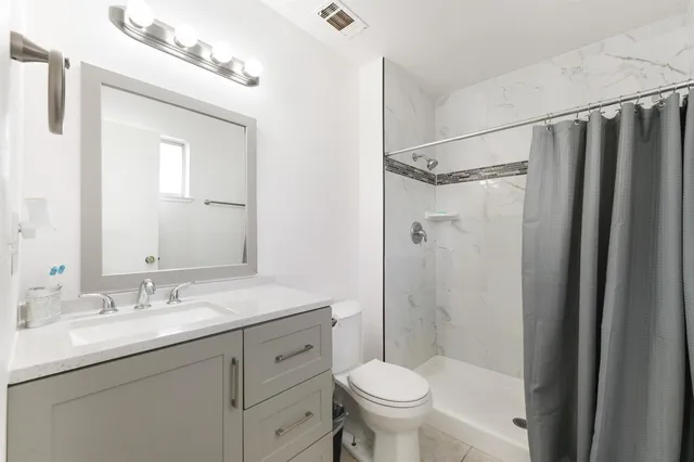 a bathroom with a shower sink vanity mirror and toilet
