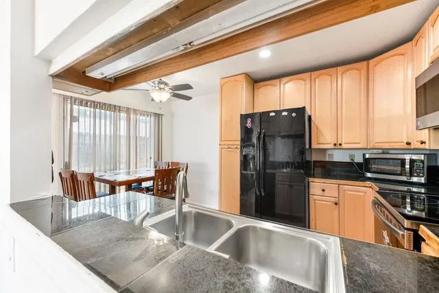 a kitchen with stainless steel appliances granite countertop a refrigerator a stove and white cabinets with wooden floor