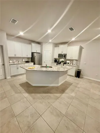 a large kitchen with kitchen island a stove a sink dishwasher a refrigerator and white cabinets with wooden floor