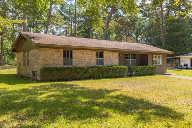 a view of house with garden and tall trees