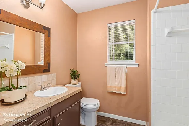 a bathroom with a granite countertop sink toilet and mirror