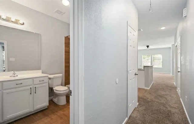 a bathroom with a granite countertop toilet a sink and a mirror