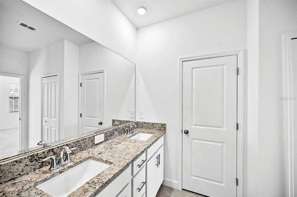 14812 Lyla Terrace Lakewood Ranch, FL 34211 - Photo 22 of 65 a bathroom with a granite countertop double vanity and a mirror