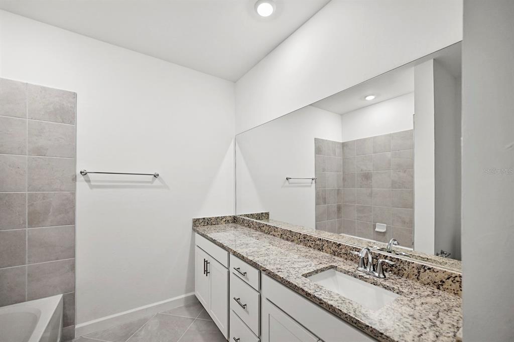 14812 Lyla Terrace Lakewood Ranch, FL 34211 - Photo 24 of 65 a bathroom with a granite countertop sink a mirror and a shower
