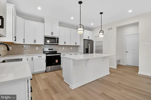 a large kitchen with stainless steel appliances granite countertop a stove a sink a refrigerator a center island a stove and a wooden floors