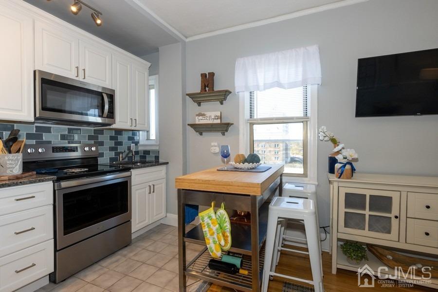 400 Deal Lake Drive, Unit 4G Asbury Park, NJ 07712 - Photo 13 of 20 a kitchen with stainless steel appliances kitchen island granite countertop a stove a sink and a microwave