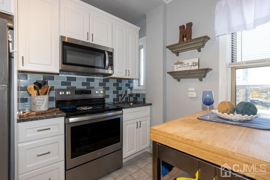 400 Deal Lake Drive, Unit 4G Asbury Park, NJ 07712 - Photo 15 of 20 a kitchen with stainless steel appliances granite countertop a stove a microwave and wooden cabinets