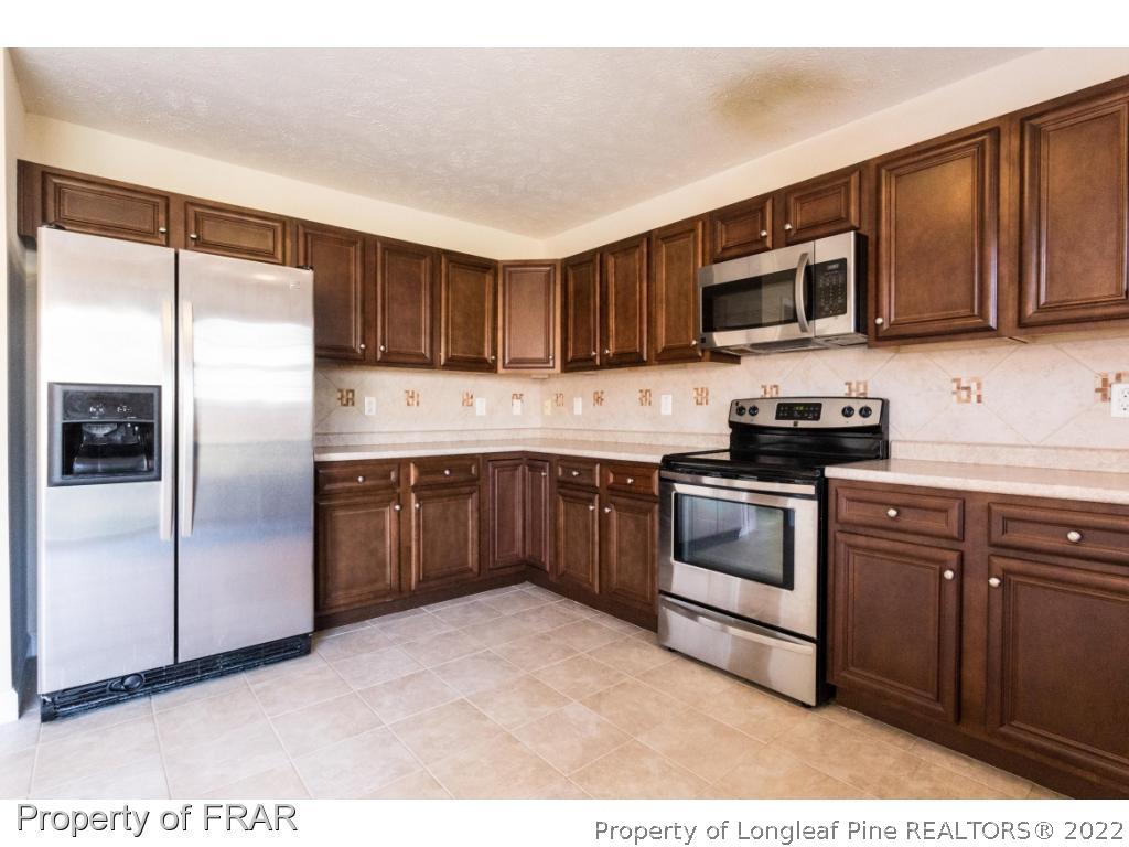 47 Rockingham Street Spring Lake, NC 28390 - Photo 10 of 27 a kitchen with stainless steel appliances granite countertop a refrigerator stove a sink and dishwasher with wooden cabinet