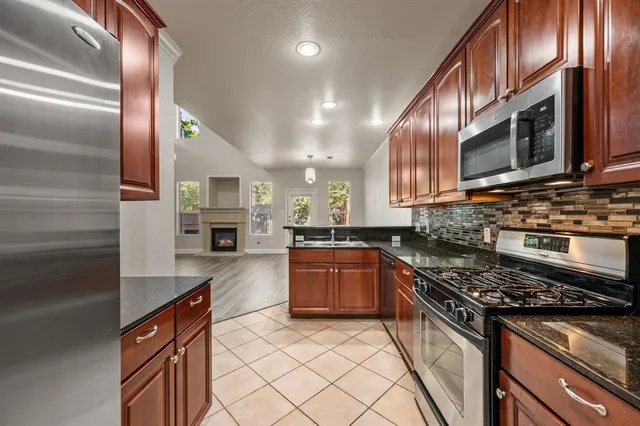 a kitchen with stainless steel appliances granite countertop a stove a sink and a microwave