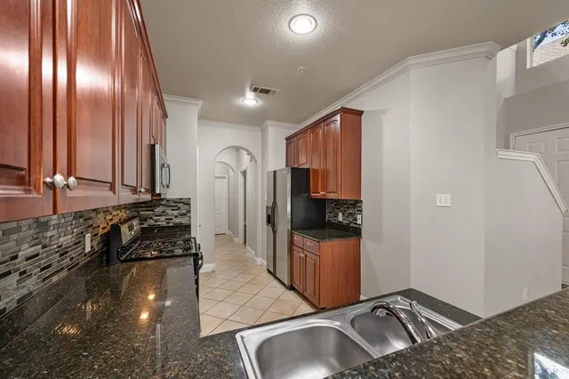 a view of a kitchen with stainless steel appliances granite countertop a sink and a refrigerator