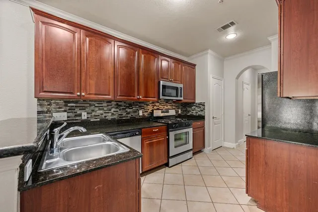 a kitchen with granite countertop a sink stove and refrigerator