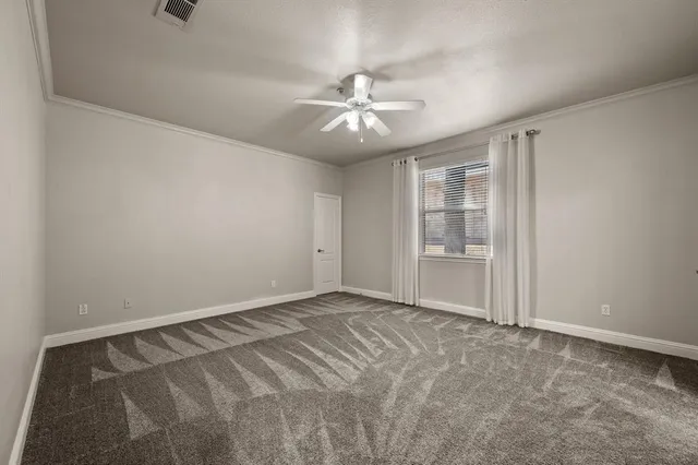 a view of an empty room with chandelier fan and fire place