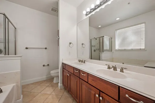 a spacious bathroom with a double vanity sink a mirror and a toilet