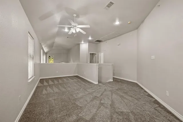 an empty room with chandelier fan and windows