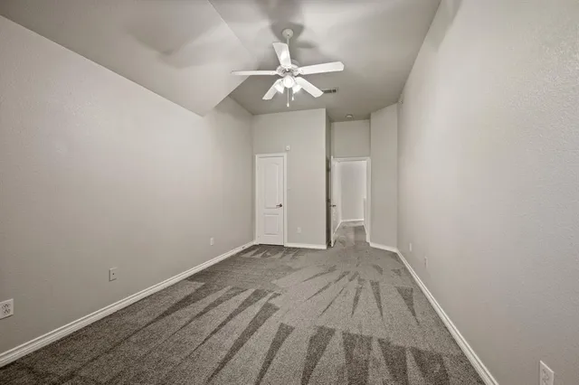 a view of an empty room with wooden floor and a ceiling fan