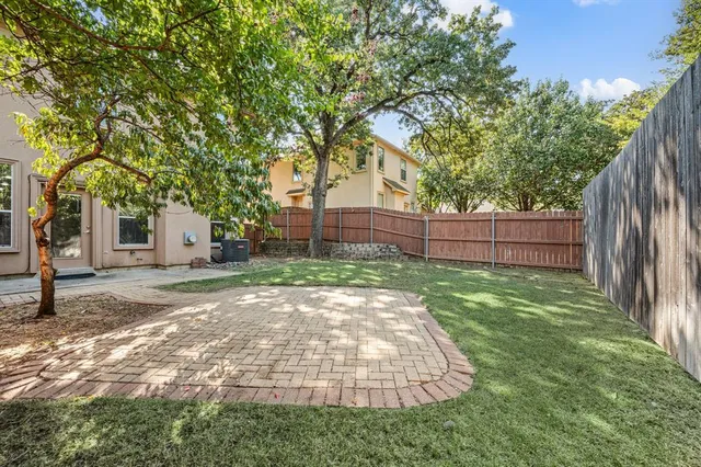 a view of a backyard with wooden fence and a large tree