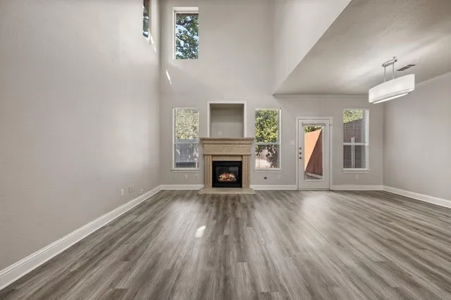 an empty room with wooden floor fireplace and windows
