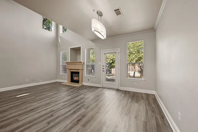 an empty room with wooden floor fireplace and windows
