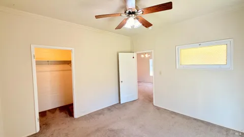 en empty room with closet and a chandelier fan