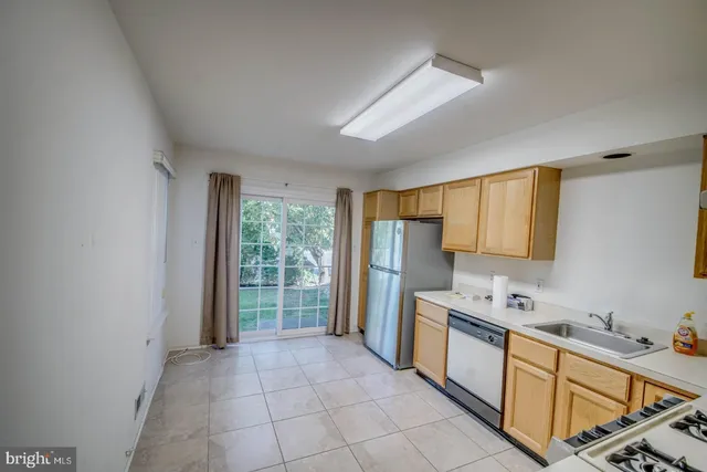 a kitchen with stainless steel appliances a refrigerator a sink a stove top oven and a window