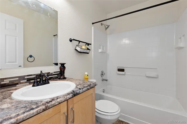 a bathroom with a granite countertop sink a toilet a mirror a vanity and shower
