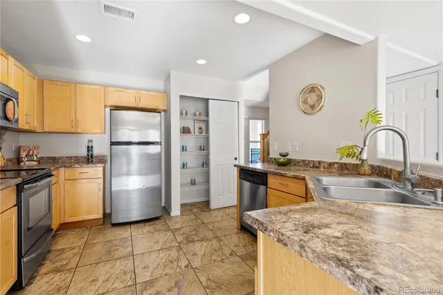 a kitchen with stainless steel appliances granite countertop a sink a stove a refrigerator cabinets and a counter top space