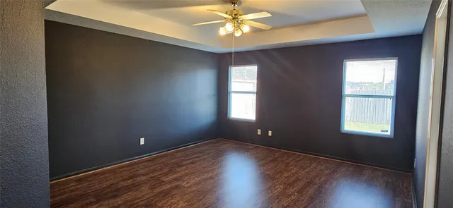 an empty room with wooden floor and windows