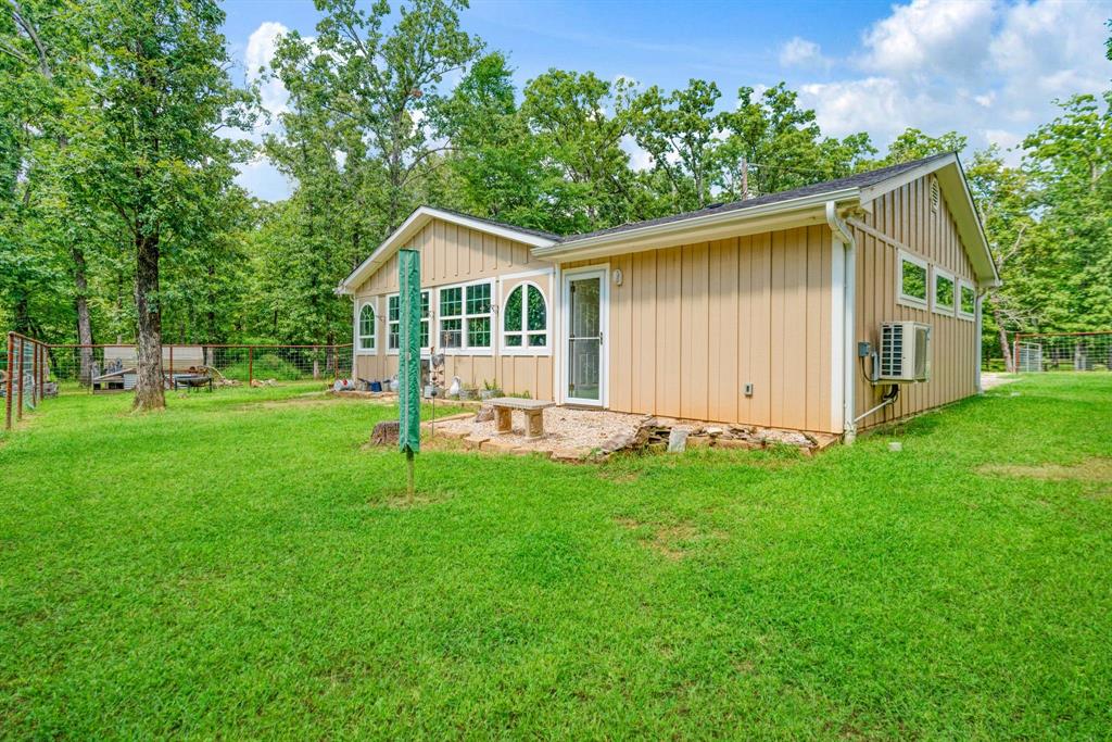 821 County Road Paris, TX 75462 - Photo 33 of 40 Expansive green lawn surrounds a tan-sided structure with multiple windows