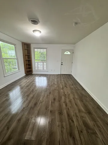 an empty room with wooden floor and windows