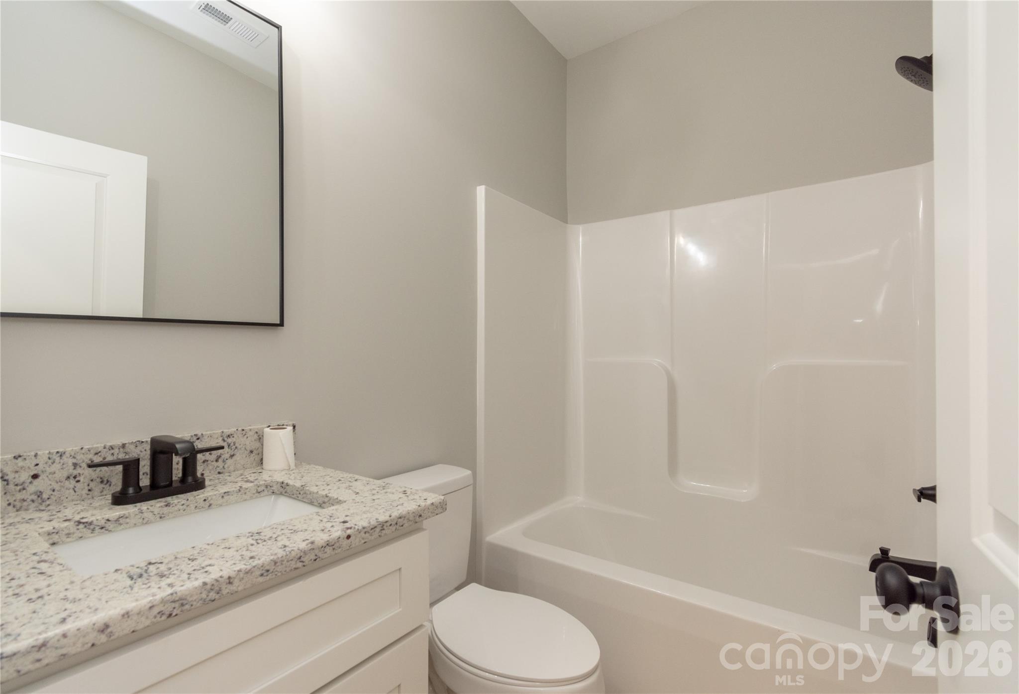 472 Oak Road Norwood, NC 28128 - Photo 14 of 27 a bathroom with a granite countertop sink toilet a mirror and bathtub
