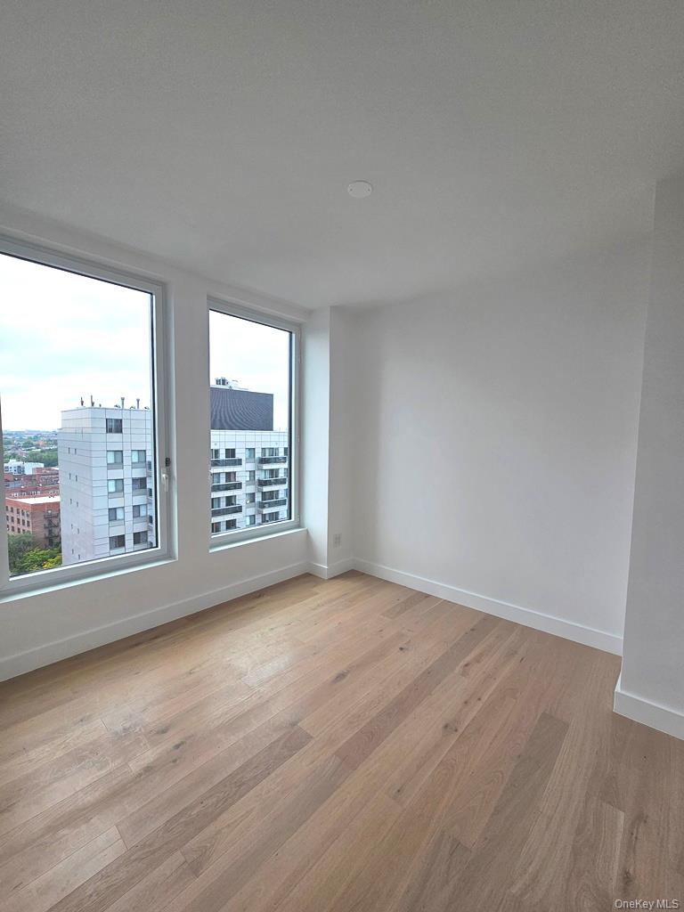 136-18 Maple Avenue, Unit 16A Queens, NY 11355 - Photo 1 of 15 a view of an empty room with a window and wooden floor