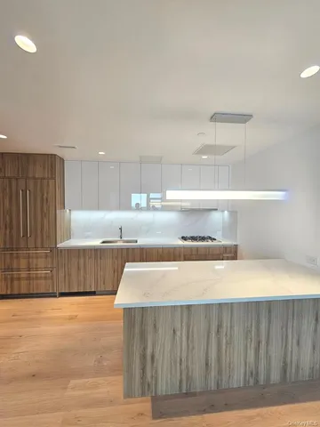a view of a kitchen with kitchen island a sink wooden floor and glass windows