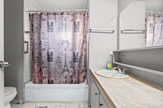 a bathroom with a granite countertop sink a toilet a mirror and shower