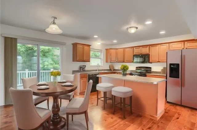 a kitchen with stainless steel appliances granite countertop a stove a refrigerator a kitchen island a dining table and chairs