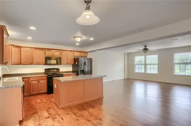 a kitchen with stainless steel appliances granite countertop a stove top oven a sink dishwasher a dining table and chairs with wooden floor