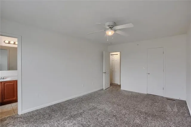a view of an empty room with a ceiling fan and window