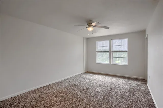 an empty room with windows and ceiling fan