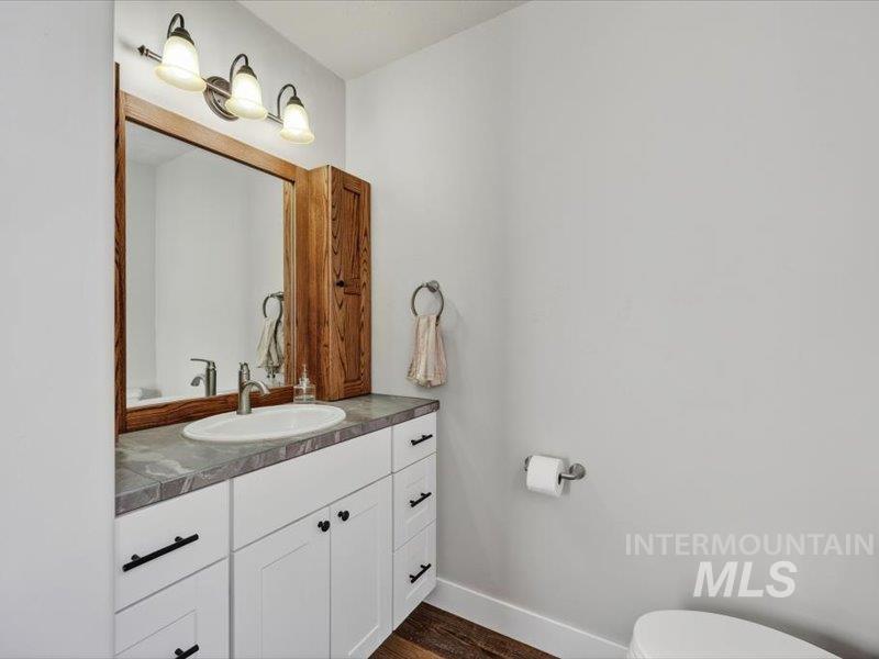 2651 Fruitvale Glendale Road Council, ID 83612 - Photo 15 of 24 Powder room featuring a white vanity with black hardware, a contrasting gray countertop, and an oval undermount sink with a brushed nickel faucet