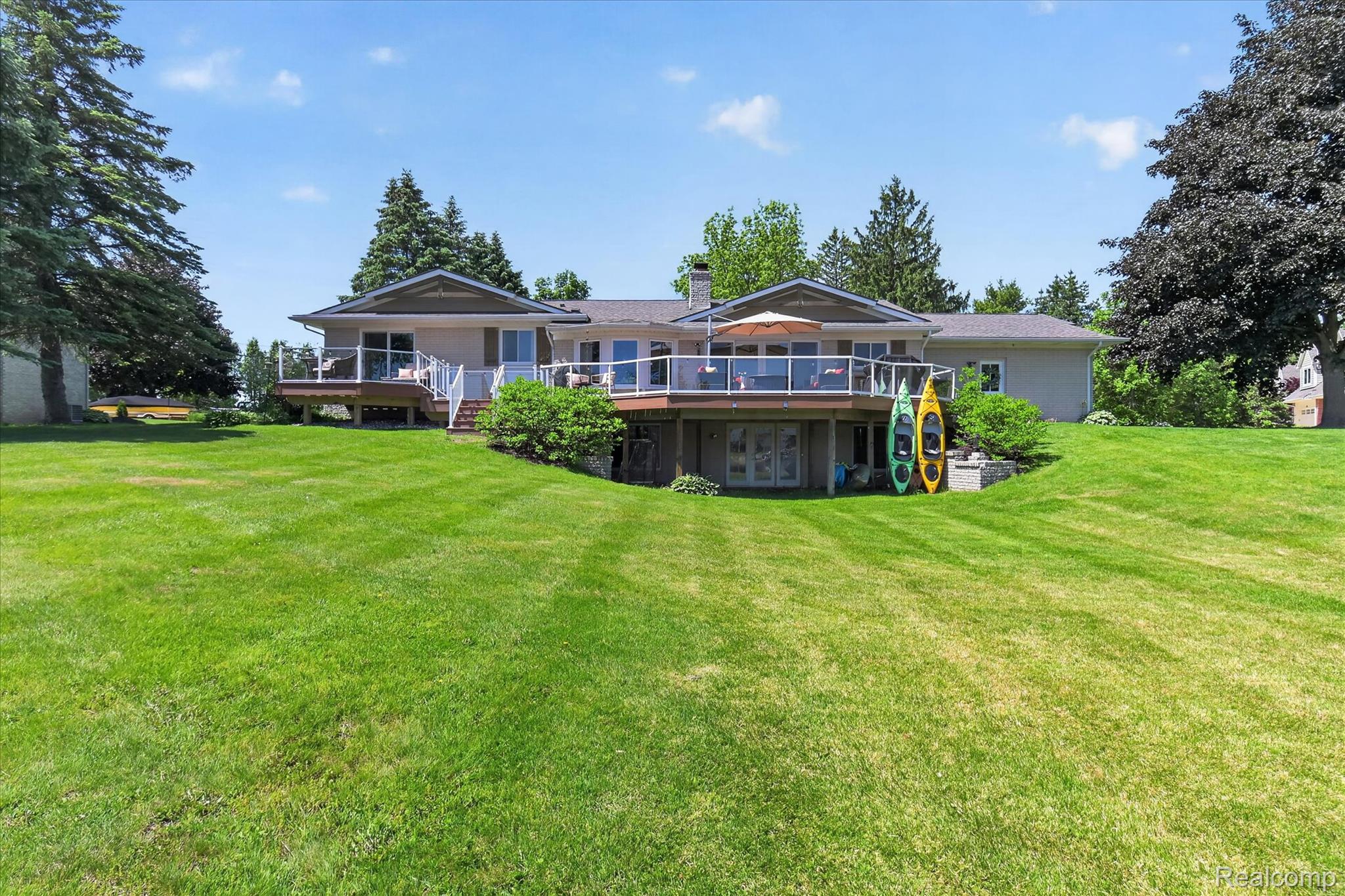 3860 East Commerce Road Commerce Township, MI 48382 - Photo 55 of 72 Expansive grassy lawn complementing a multi-level residence with a large elevated deck featuring glass panel railings