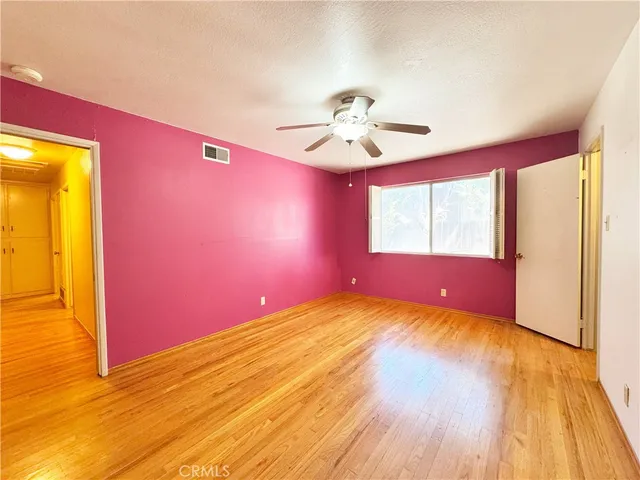 a view of empty room with wooden floor and fan