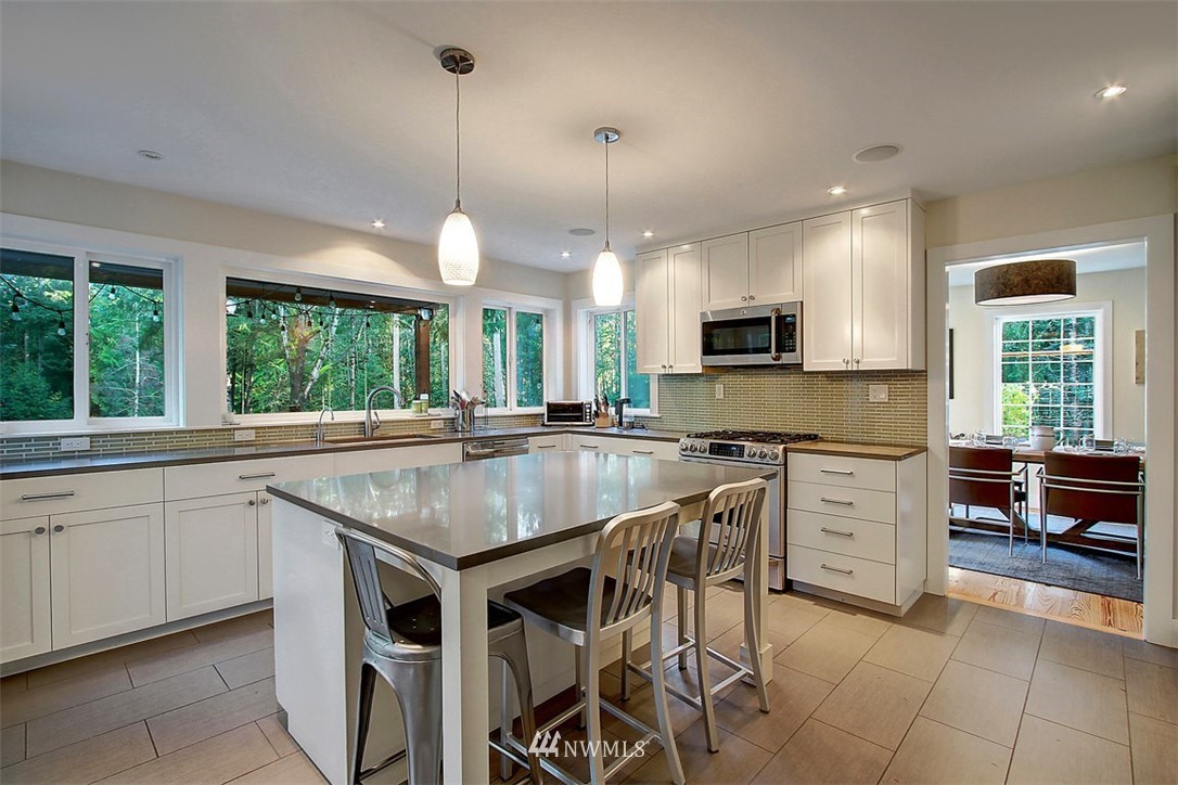 6615 Cultus Bay Road Clinton, WA 98236 - Photo 3 of 25 a kitchen with stainless steel appliances granite countertop a stove top oven a sink dishwasher a dining table and chairs with wooden floor