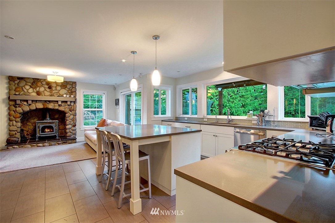6615 Cultus Bay Road Clinton, WA 98236 - Photo 4 of 25 a kitchen with stainless steel appliances granite countertop a stove top oven a sink dishwasher and a fireplace with wooden floor