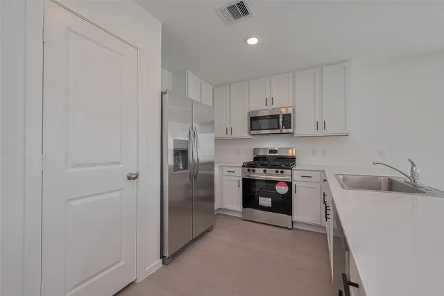 a kitchen with stainless steel appliances granite countertop a refrigerator stove and a sink