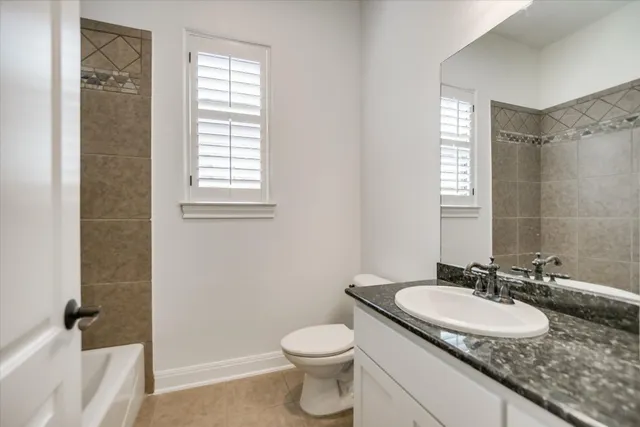 a bathroom with a granite countertop sink toilet and a mirror