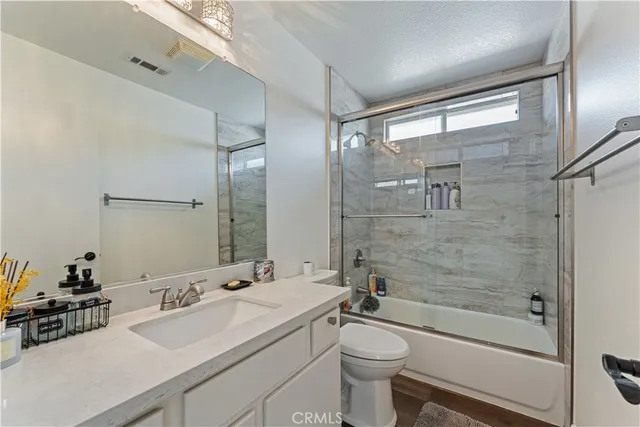 a bathroom with a sink a toilet a mirror and shower