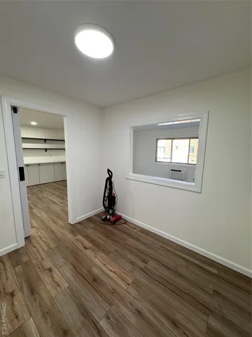 a view of an empty room with a window and wooden floor
