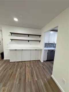 a kitchen with wooden floors and white cabinets